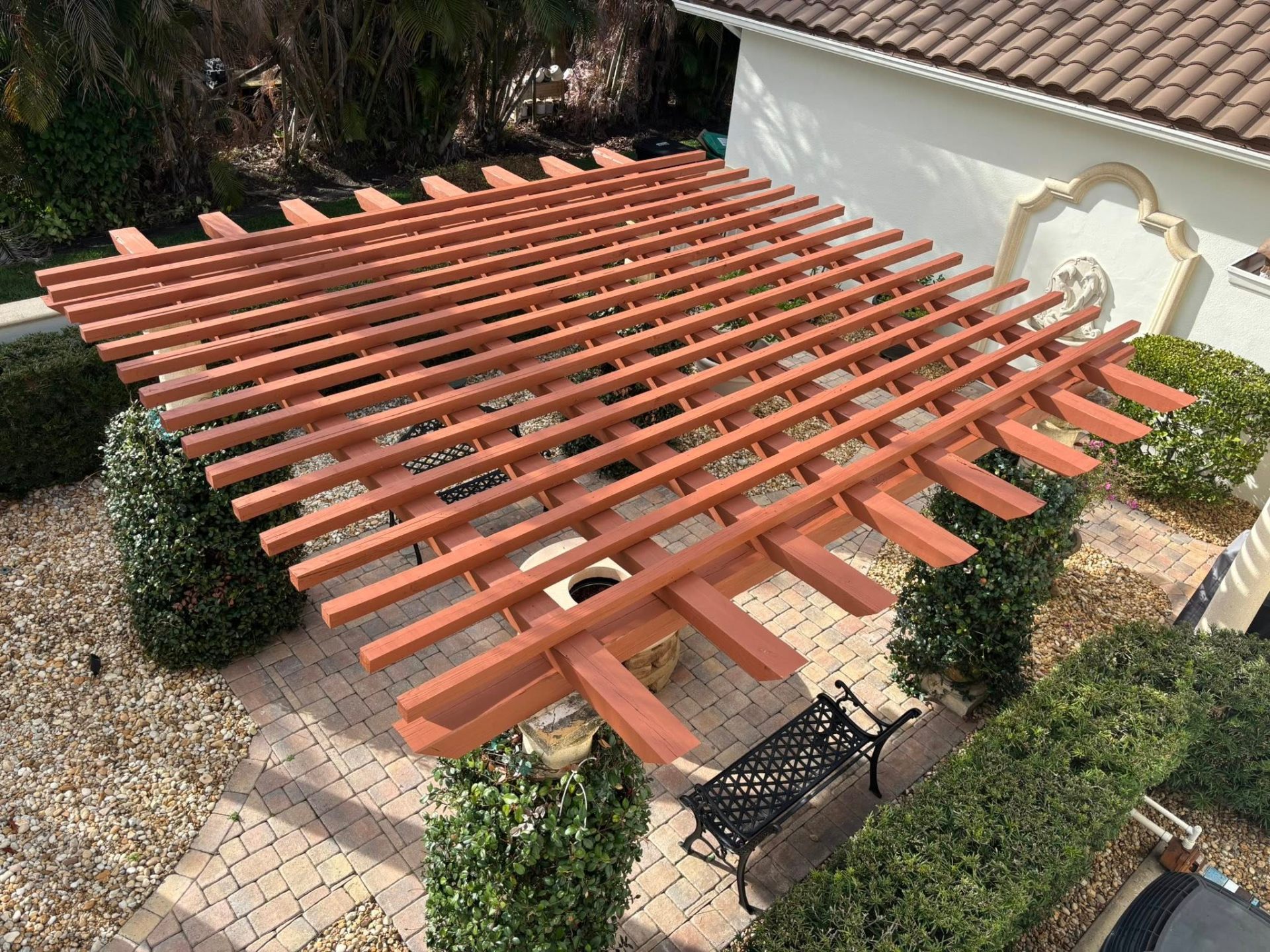 Freshly stained wood pergola over a paver patio at a Treasure Coast home by Millman Services.