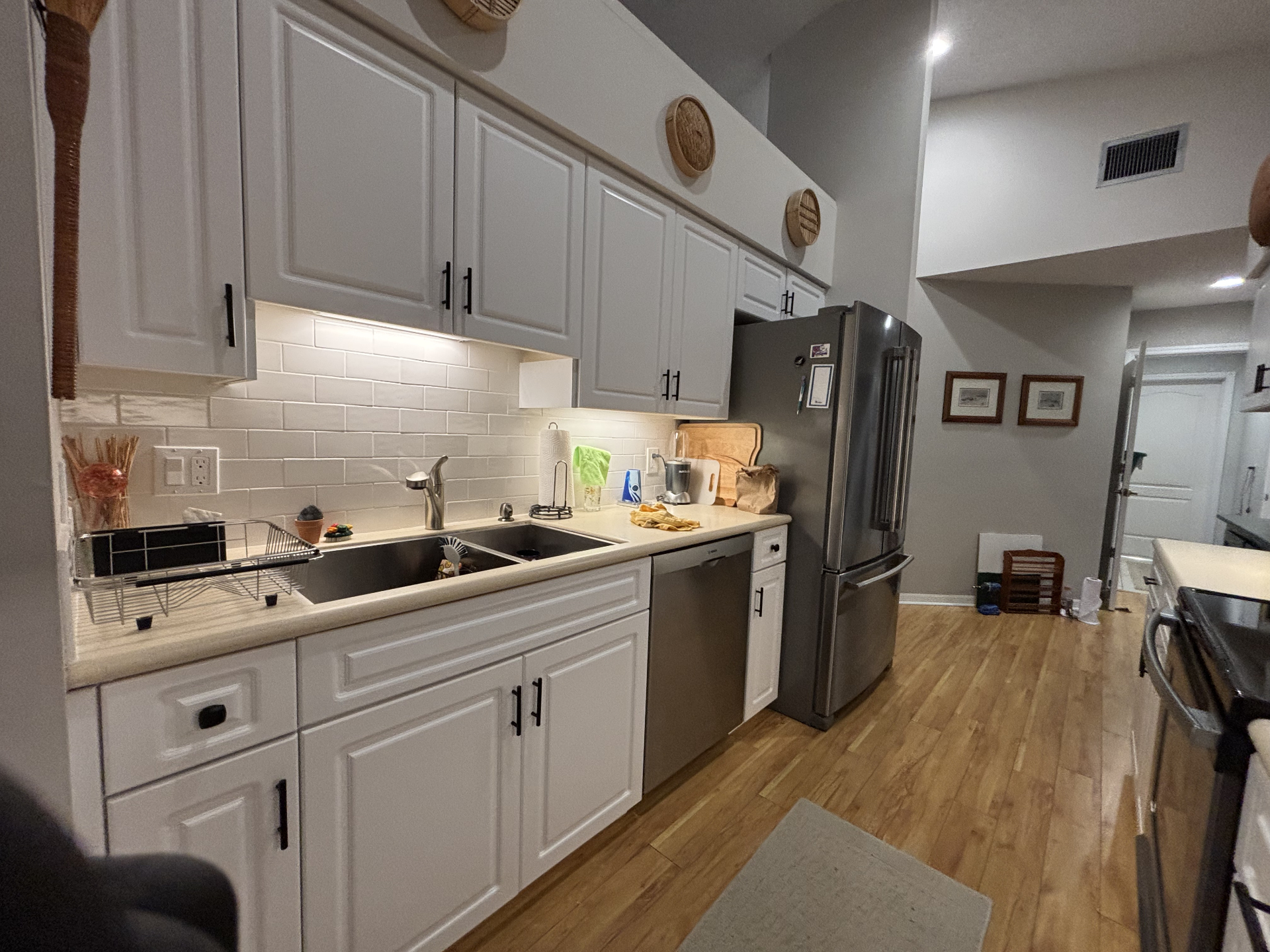 Refaced white kitchen cabinets with subway tile backsplash in a Treasure Coast condo by Millman Services