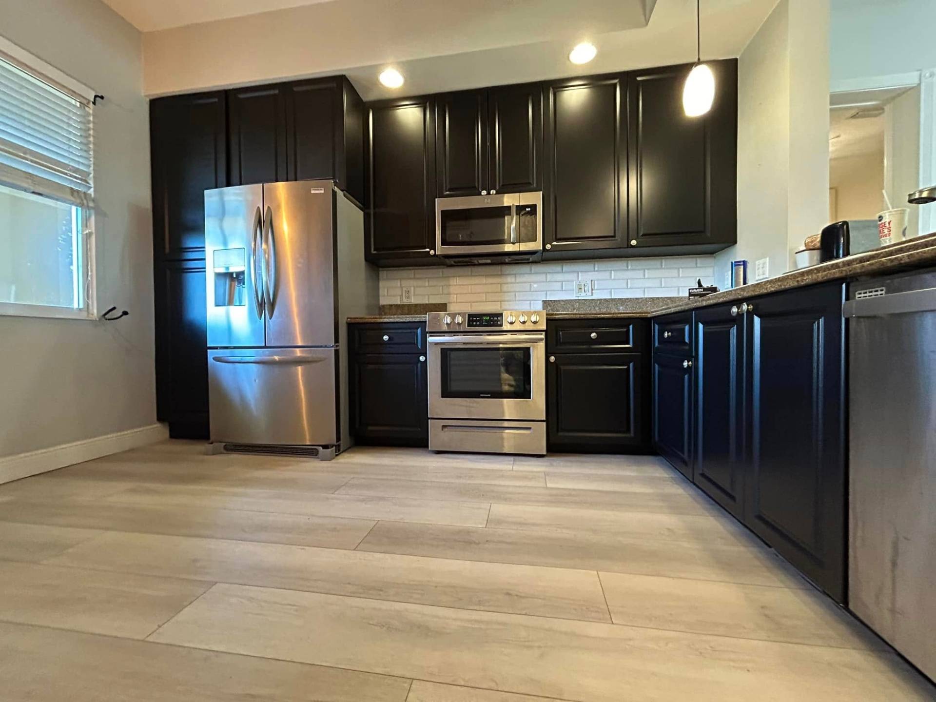Dark espresso-painted kitchen cabinets with stainless appliances refinished by Millman Services on the Treasure Coast
