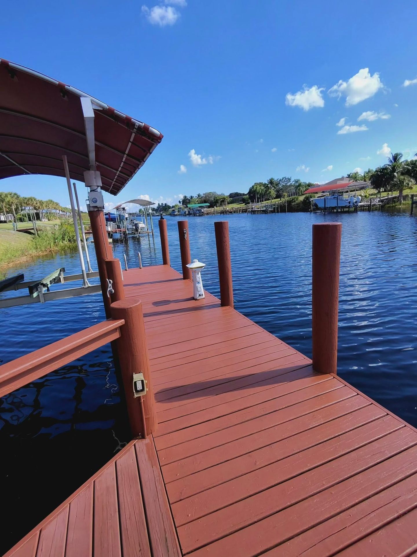 Freshly stained waterfront dock in a rich red-brown finish by Millman Services on the Treasure Coast.